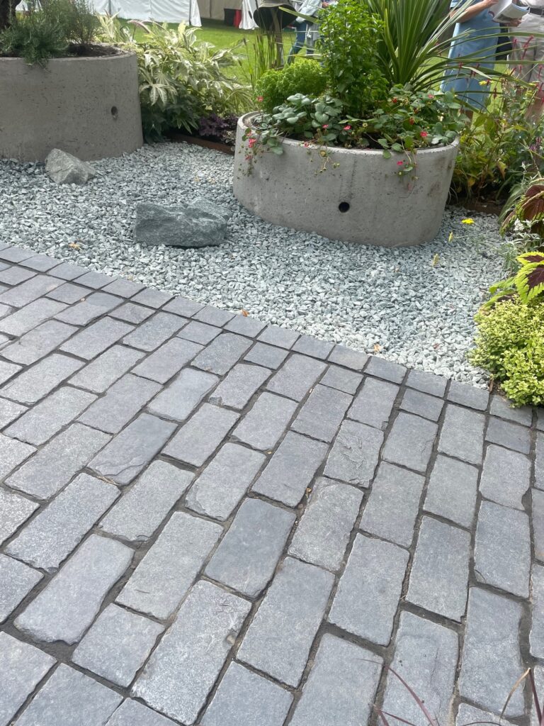 grey limestone cobble patio leading to grey gravel area with stone trough planter