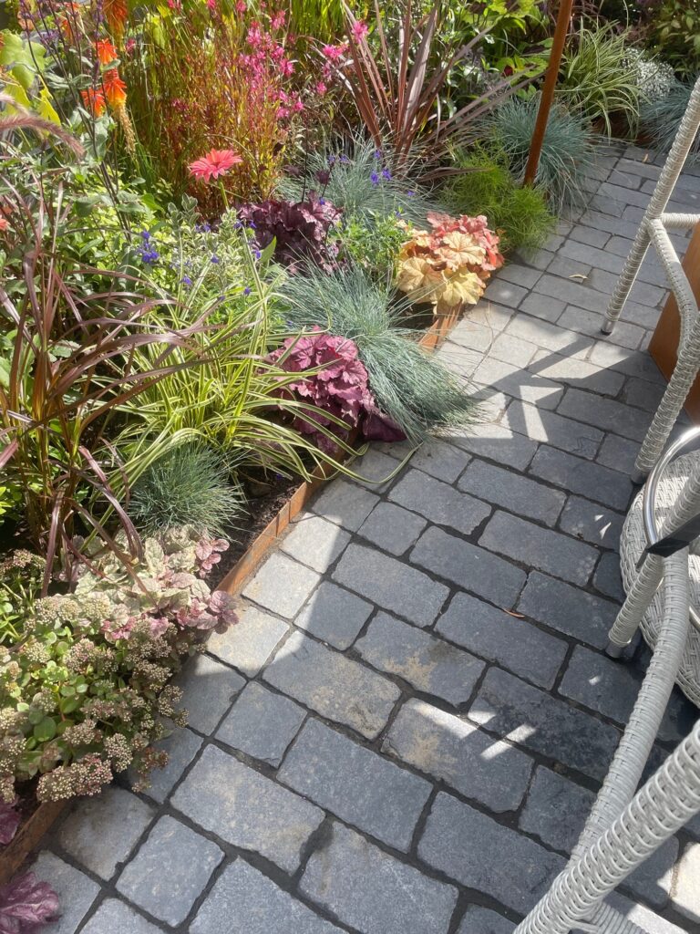 grey limestone cobble path borederd by colourful pat to the left.